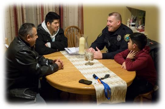 Brooklyn Park Police Department officer sits with family around table